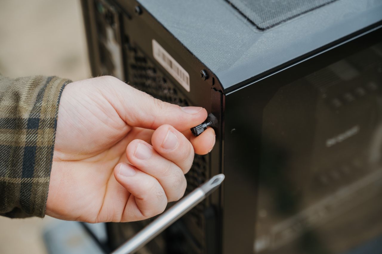 About Close-up of a hand unscrewing a desktop computer case, emphasizing technology maintenance.